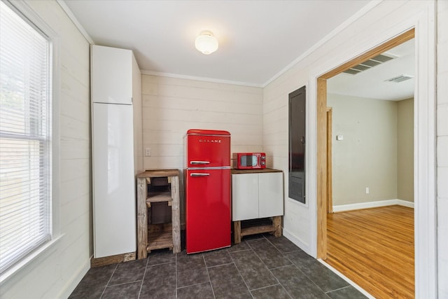 laundry area featuring dark tile patterned flooring and crown molding