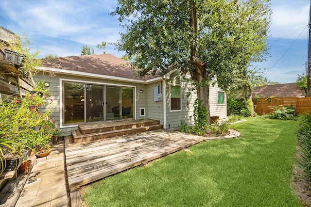 rear view of house featuring a lawn and a deck