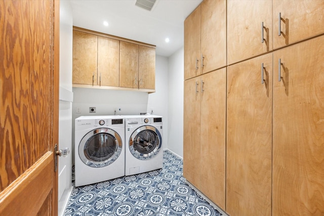 laundry room featuring washer and dryer, dark tile patterned floors, and cabinets