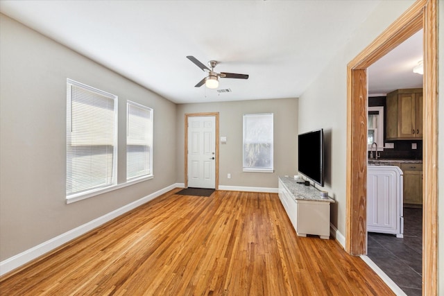 unfurnished living room with ceiling fan, light hardwood / wood-style flooring, plenty of natural light, and sink