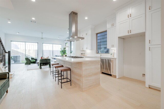 kitchen featuring a kitchen island, white cabinetry, island exhaust hood, and stainless steel appliances