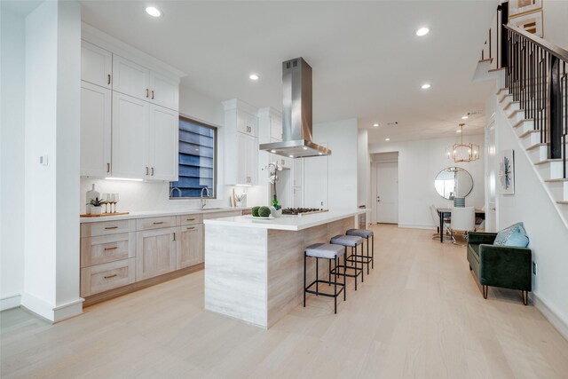 kitchen featuring white cabinetry, a large island, light hardwood / wood-style flooring, and extractor fan