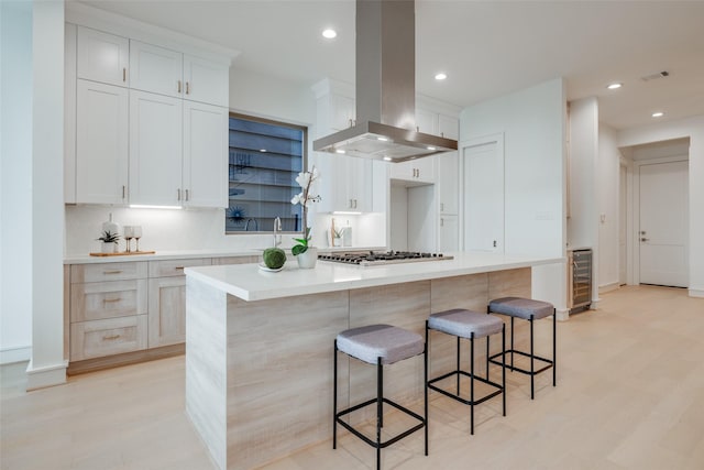 kitchen featuring a center island, white cabinetry, island exhaust hood, and wine cooler