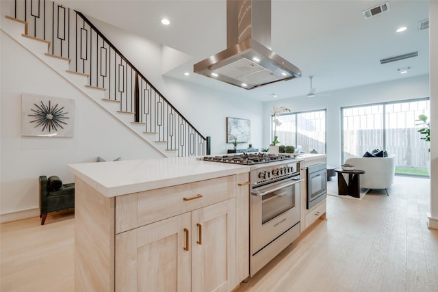 kitchen featuring appliances with stainless steel finishes, light wood-type flooring, light brown cabinetry, island range hood, and ceiling fan