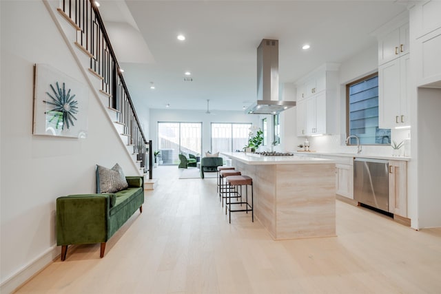 kitchen with appliances with stainless steel finishes, a breakfast bar, extractor fan, a center island, and white cabinetry