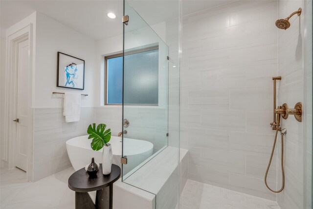 bathroom with tile walls and shower with separate bathtub