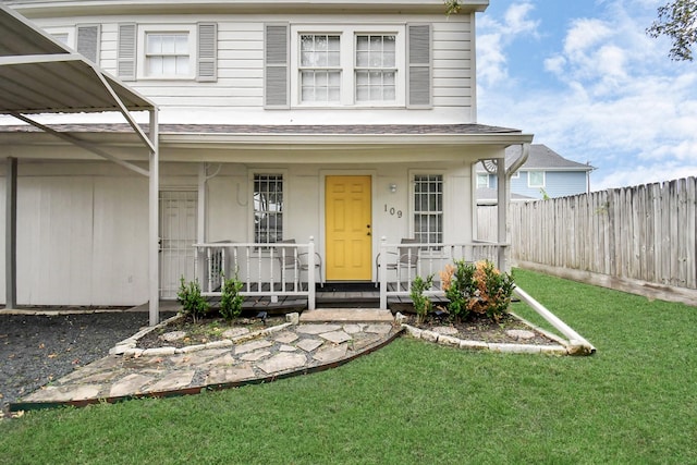 view of exterior entry with a lawn and a porch