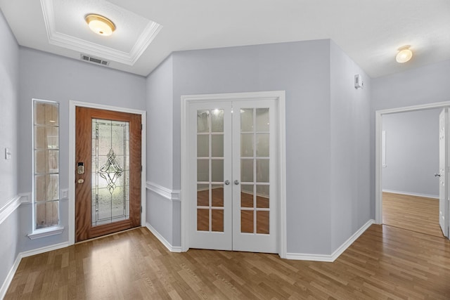 doorway with french doors, a tray ceiling, crown molding, and wood-type flooring