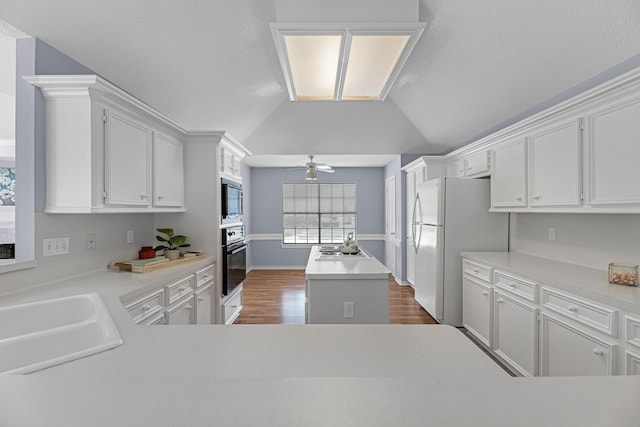 kitchen featuring oven, sink, a kitchen island, built in microwave, and white fridge