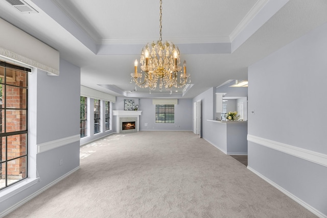 unfurnished living room with a raised ceiling, crown molding, carpet flooring, and an inviting chandelier