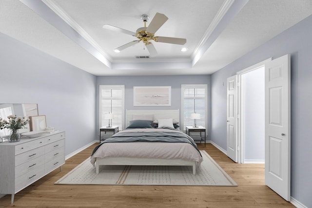 bedroom with light wood-type flooring, a raised ceiling, and ceiling fan