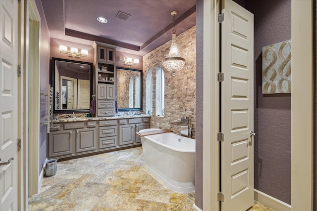 bathroom with vanity, a tray ceiling, and a bathtub