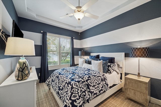 bedroom with ceiling fan and a tray ceiling