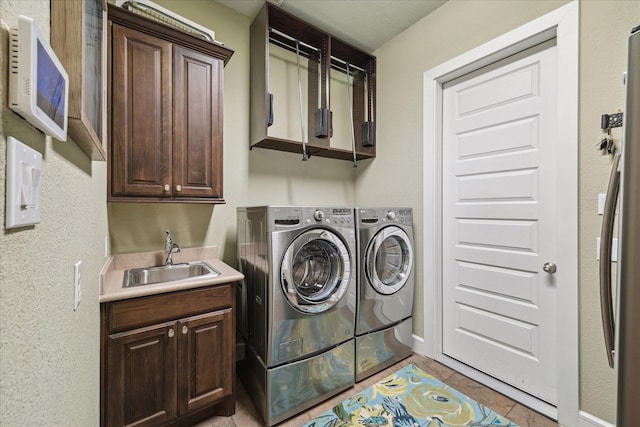 clothes washing area with cabinets, washer and clothes dryer, and sink