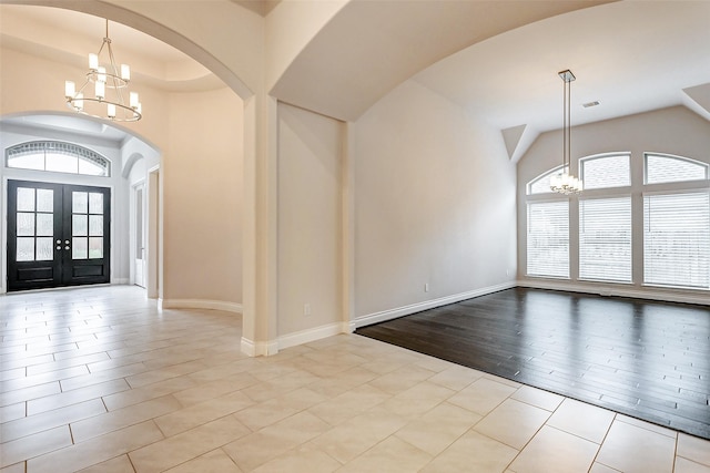 tiled foyer entrance with french doors and a notable chandelier