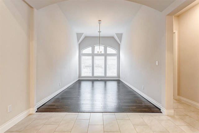 tiled spare room featuring vaulted ceiling