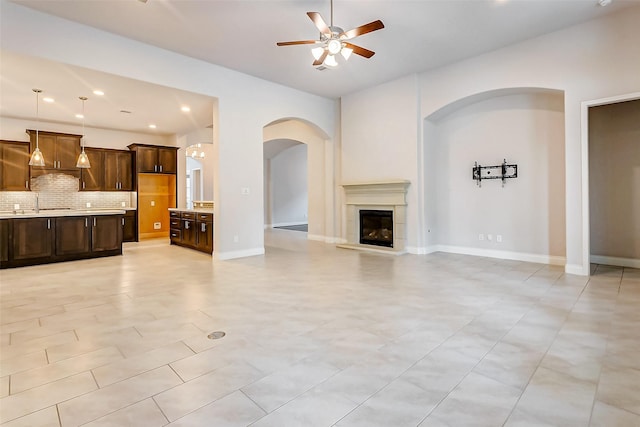 unfurnished living room featuring ceiling fan and light tile patterned floors