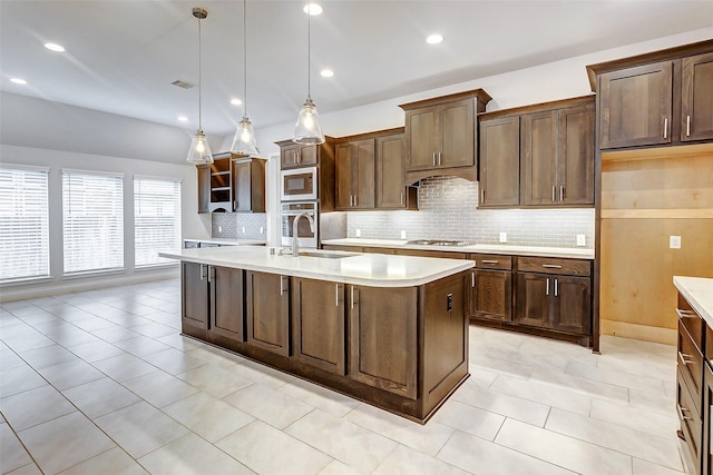 kitchen featuring a kitchen island with sink, hanging light fixtures, sink, appliances with stainless steel finishes, and dark brown cabinetry