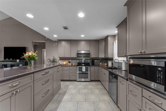 kitchen featuring appliances with stainless steel finishes, dark stone countertops, gray cabinetry, and sink