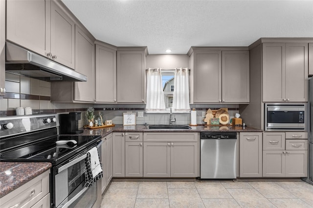 kitchen with gray cabinetry, dark stone counters, sink, a textured ceiling, and stainless steel appliances