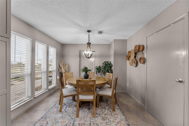 tiled dining space featuring a chandelier and a textured ceiling