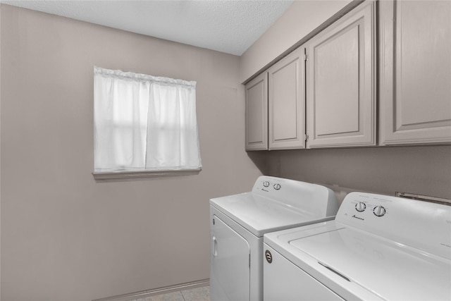 laundry area featuring washer and dryer, cabinets, and a textured ceiling