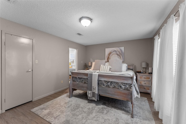 bedroom featuring light hardwood / wood-style floors and a textured ceiling