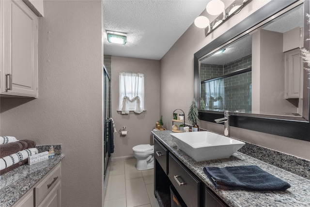 bathroom with tile patterned flooring, a textured ceiling, toilet, vanity, and a shower with shower door