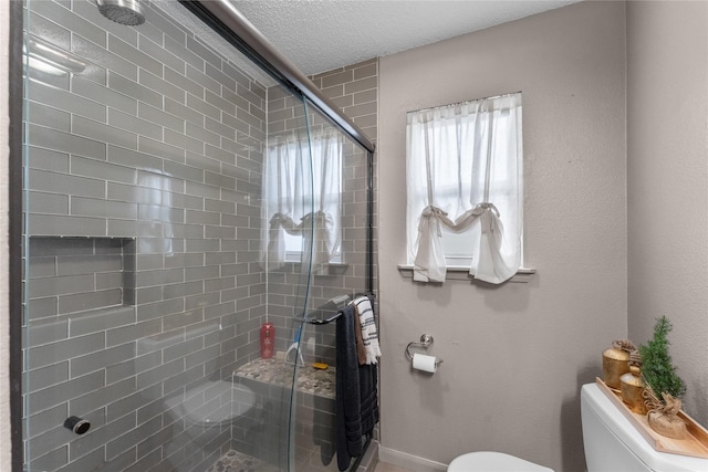 bathroom featuring a shower with shower door, a textured ceiling, and toilet