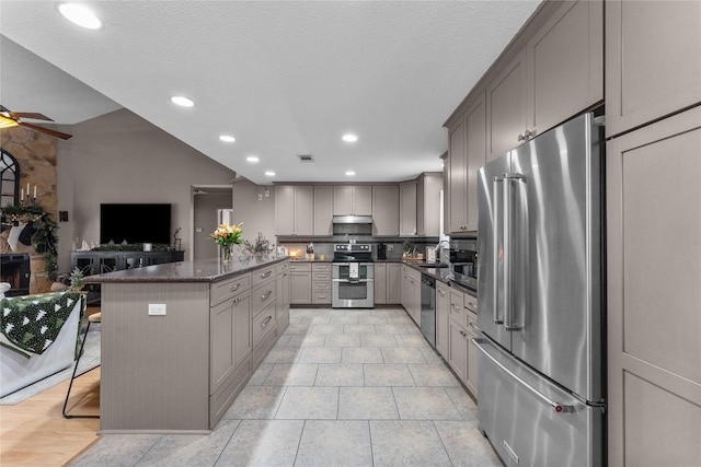 kitchen with gray cabinetry, dark stone counters, stainless steel appliances, sink, and a breakfast bar area