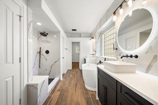 bathroom featuring vanity, a textured ceiling, and shower with separate bathtub