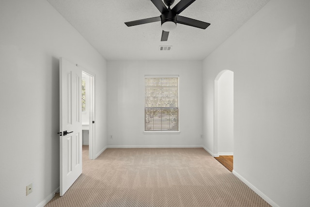 spare room featuring light carpet, a textured ceiling, and ceiling fan