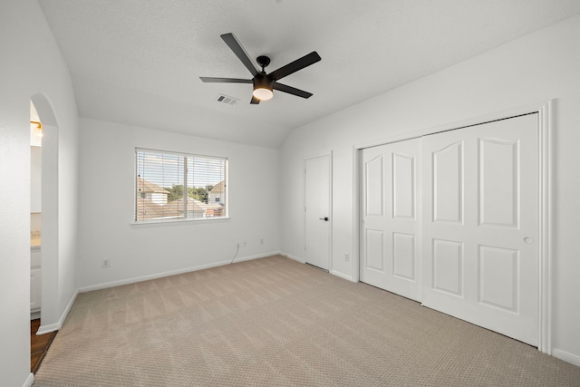 unfurnished bedroom featuring ceiling fan, light colored carpet, and vaulted ceiling