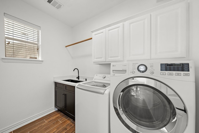 laundry area featuring cabinets, separate washer and dryer, and sink