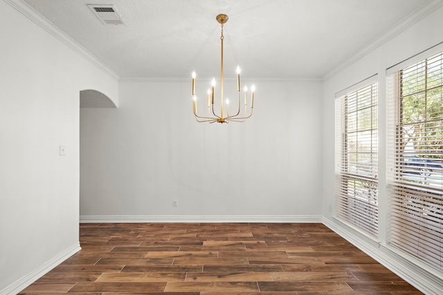 empty room featuring a chandelier, a textured ceiling, dark hardwood / wood-style floors, and ornamental molding