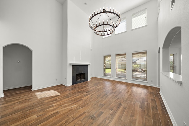 unfurnished living room featuring dark hardwood / wood-style flooring, a high ceiling, and a notable chandelier