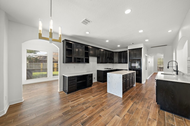 kitchen with sink, hanging light fixtures, a wealth of natural light, and tasteful backsplash