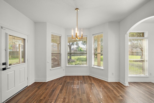 unfurnished dining area featuring dark hardwood / wood-style flooring and an inviting chandelier