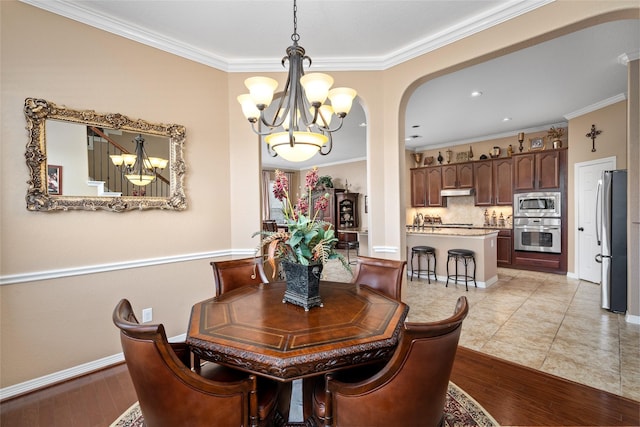 dining area with an inviting chandelier, ornamental molding, and light hardwood / wood-style flooring