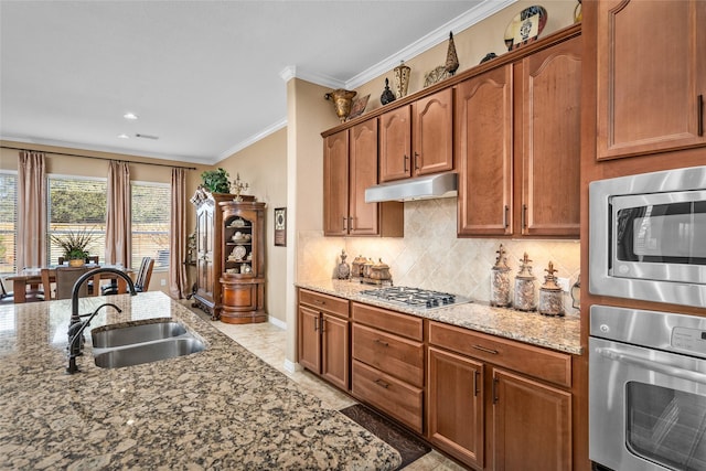 kitchen featuring stainless steel appliances, sink, light stone counters, decorative backsplash, and crown molding