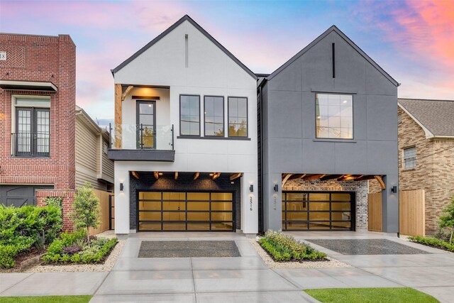 view of front facade featuring brick siding, concrete driveway, stucco siding, a balcony, and an attached garage