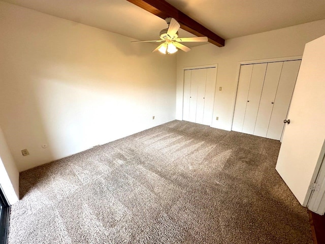 unfurnished bedroom with beamed ceiling, carpet floors, multiple closets, and ceiling fan