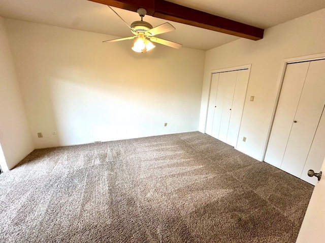 unfurnished bedroom featuring ceiling fan, carpet flooring, beam ceiling, and two closets