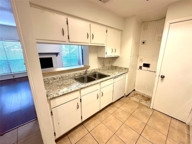 kitchen featuring light tile patterned floors, sink, dishwasher, white cabinets, and a brick fireplace