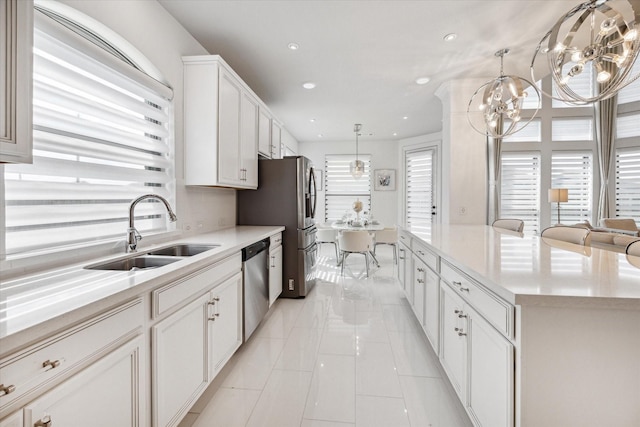 kitchen featuring sink, stainless steel appliances, a kitchen island, decorative light fixtures, and white cabinets