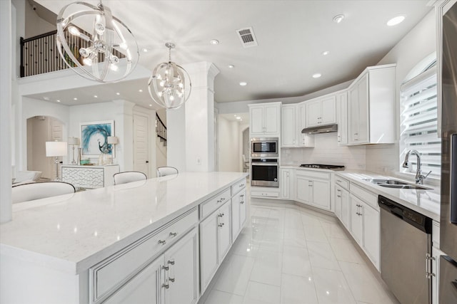 kitchen with sink, a large island, appliances with stainless steel finishes, a notable chandelier, and white cabinetry