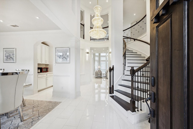 foyer entrance with light tile patterned floors, a chandelier, and ornamental molding