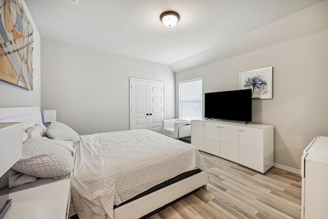 bedroom featuring light hardwood / wood-style flooring, a closet, and lofted ceiling