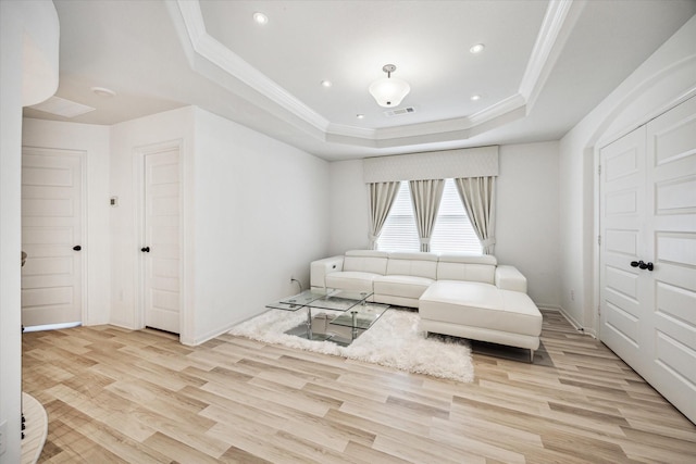 living room featuring light wood-type flooring, crown molding, and a tray ceiling