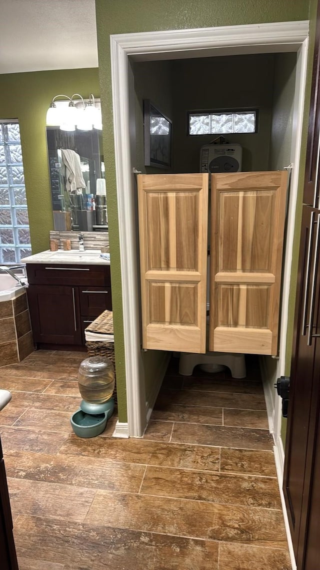 bathroom with vanity, a healthy amount of sunlight, and tiled bath